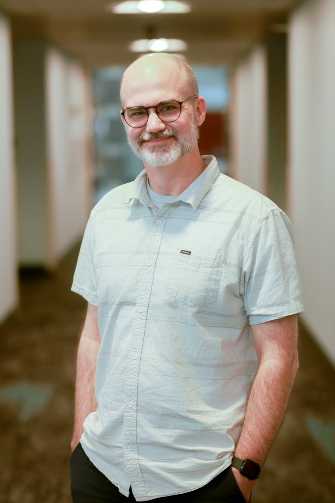 Man with beard and glasses looking at the camera.