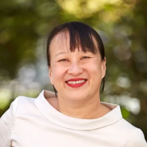 Headshot of woman with dark hair and white shirt smiling at camera.